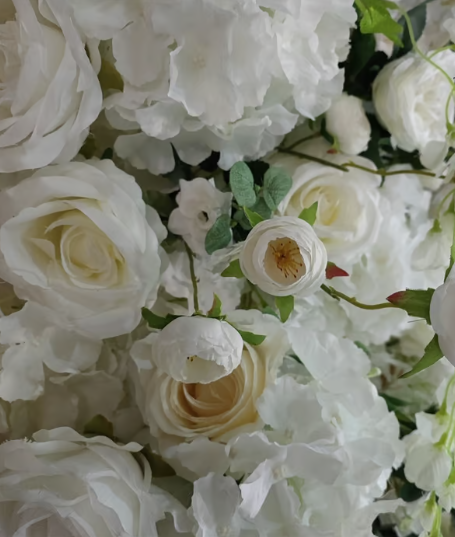 Joy A close-up of white roses and delicate blossoms with green leaves.